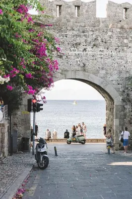 a group of people walking on a street under a stone bridge at Sunway Suite in Rhodes Town