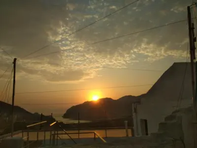 a sunset over a mountain with the sun in the sky at Marthas Traditional House in Symi