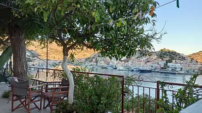 a table and chairs sitting under a tree next to a river at Pitini Sevasti house in Symi