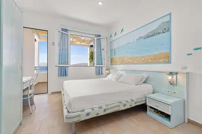 a bedroom with a bed and a desk and windows at Haraki Memories Beach Studios in Haraki