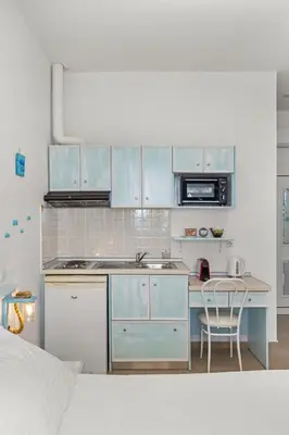 a kitchen with blue cabinets and a sink and a table at Haraki Memories Beach Studios in Haraki