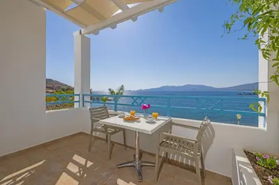 a balcony with a table and chairs and a view of the ocean at Haraki Memories Beach Studios in Haraki