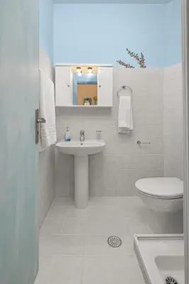 a white bathroom with a sink and a toilet at Haraki Memories Beach Studios in Haraki