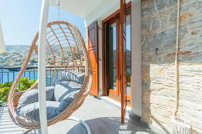 a hanging rattan chair on a balcony with a view at Villa Ioanna in Symi
