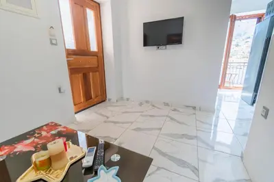 a living room with a table and a television on a wall at Villa Ioanna in Symi