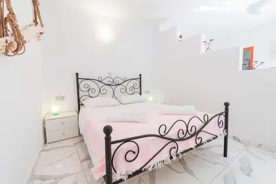 a white bedroom with a black and pink bed at Villa Ioanna in Symi
