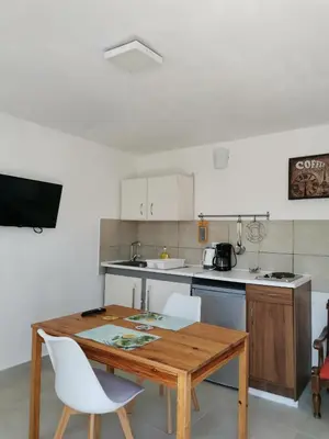 a kitchen with a wooden table and white chairs at Loft for 2 in Rhodes town near Elli beach in Rhodes Town