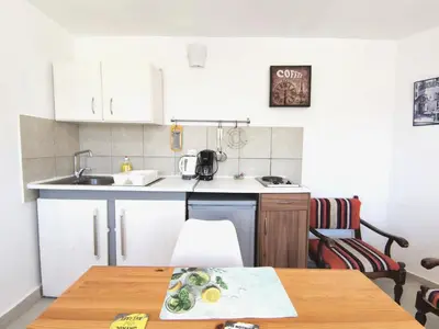 a kitchen with white cabinets and a wooden table at Loft for 2 in Rhodes town near Elli beach in Rhodes Town