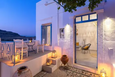 a house with a balcony with a table and chairs at Lindos Beach Boutique Villa in Líndos