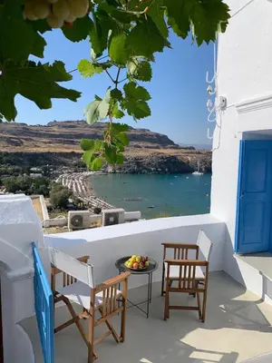 a balcony with chairs and a table and water at Lindos Beach Boutique Villa in Líndos