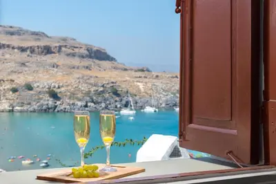 two champagne glasses sitting on a table with a view of the ocean at Lindos Beach Boutique Villa in Líndos