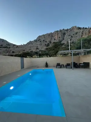 a blue swimming pool on a patio with a mountain at Tesoro Del Mare in Pefki Rhodes