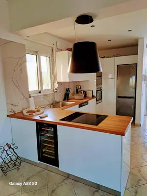 a kitchen with white cabinets and a black hood at S-EVA RESORT in Kolimbia