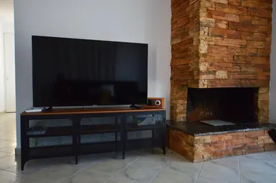 a large flat screen tv on a stand in front of a fireplace at S-EVA RESORT in Kolimbia