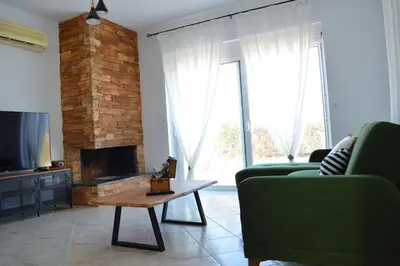 a living room with two green chairs and a fireplace at S-EVA RESORT in Kolimbia