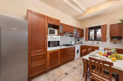 a kitchen with wooden cabinets and a table with a plate of fruit at Blue Vision Luxury House in Pefki Rhodes