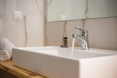 a white sink with a faucet in a bathroom at Avi Suites Faliraki in Faliraki