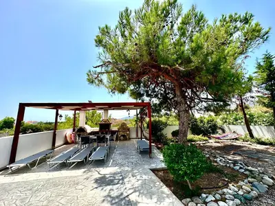 a patio with a table and chairs and a tree at Villa Papagiorgio Luxury and Harmony in Gennadi