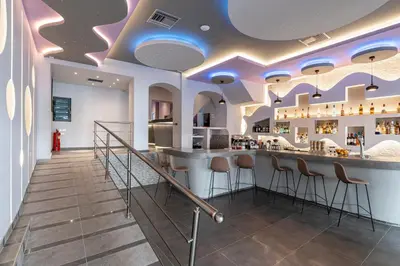 a bar with stools in a restaurant with purple ceilings at N E P center Hotel Rodos in Rhodes Town