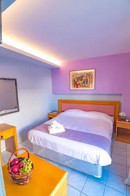 a bedroom with a bed and a basket of fruit on a table at N E P center Hotel Rodos in Rhodes Town