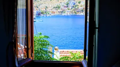 a woman looking out of a window at the water at Villa Pitini in Symi