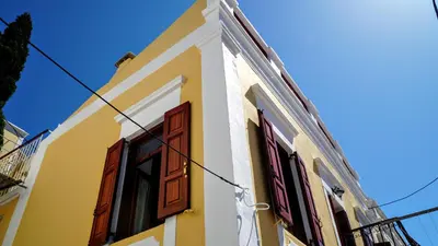 a yellow and white building with red doors at Villa Pitini in Symi