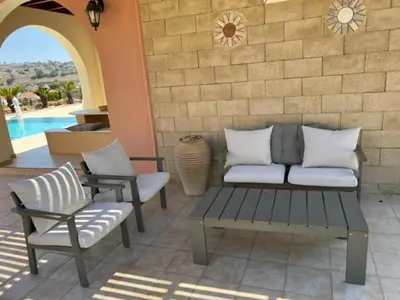a patio with a couch and chairs next to a wall at Luxury Villa Delfini in Líndos