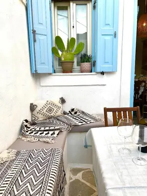 a patio with a table and a window with pillows at Aetheria traditional house in Koskinou