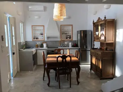 a kitchen with a table and chairs and a refrigerator at Aetheria traditional house in Koskinou