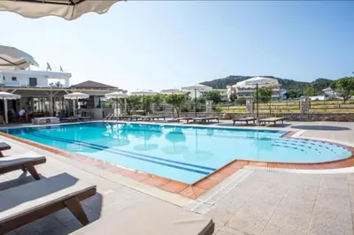 a large swimming pool in a resort with tables and chairs at Vickys Faliraki in Faliraki