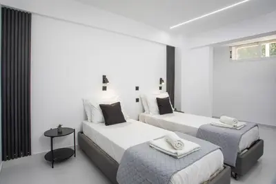 two beds in a room with white walls at Vickys Faliraki in Faliraki