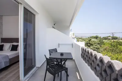 a balcony with a table and chairs and a bed at Vickys Faliraki in Faliraki