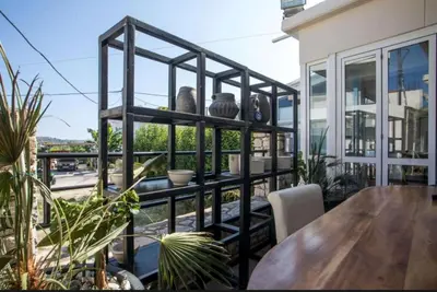 a black shelving unit on a balcony with a table at Vickys Faliraki in Faliraki