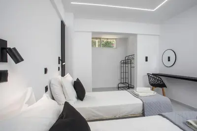 a white room with two beds and a table at Vickys Faliraki in Faliraki