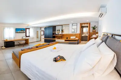 a bedroom with a large white bed and a living room at IN Lindos in Líndos