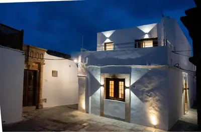 a white building at night with lights on at IN Lindos in Líndos