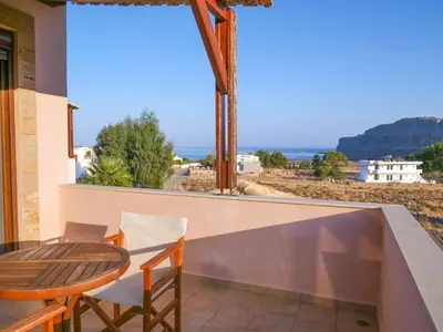 a balcony with a table and chairs and a view of the ocean at Luxury Villa Ioannis in Líndos