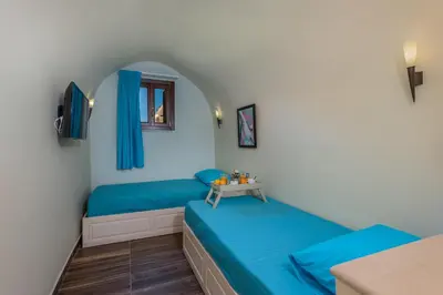 a room with two beds and a table at BIBLIOTHEQUE in Rhodes Town