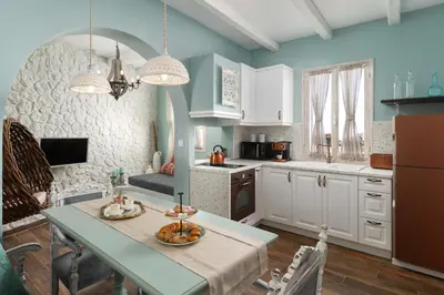 a kitchen with white cabinets and a table with fruits on it at Casa Pietra Lindos Luxury Traditional House in Líndos