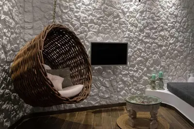 a wicker chair in a living room with a tv at Casa Pietra Lindos Luxury Traditional House in Líndos
