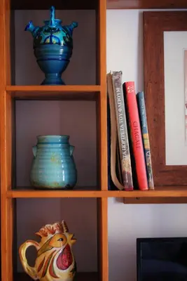 a book shelf with a blue vase and books at the bougainvillea house in Symi