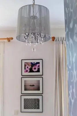 a chandelier hangs above three framed pictures on a wall at the bougainvillea house in Symi