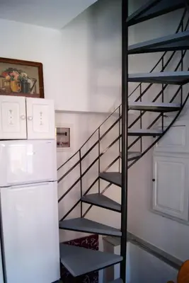 a spiral staircase in a kitchen next to a refrigerator at the bougainvillea house in Symi