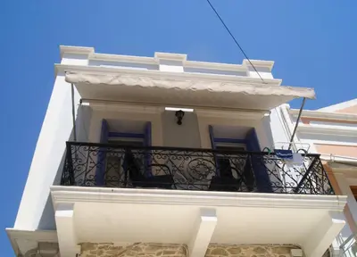 a white building with a balcony at the bougainvillea house in Symi