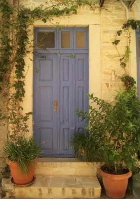a purple door on a building with potted plants at the bougainvillea house in Symi