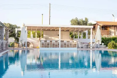 a swimming pool with umbrellas and a house at Evita in Faliraki