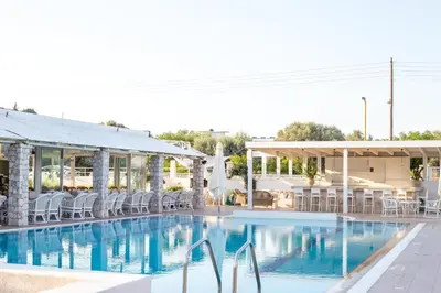 a pool at a hotel with chairs and tables at Evita in Faliraki