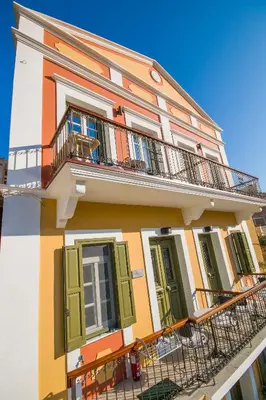 a building with green shutters and a balcony at Thea in Symi
