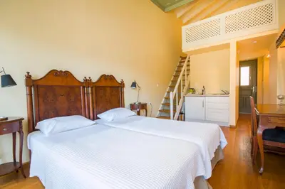 a bedroom with a large white bed and a kitchen at Thea in Symi