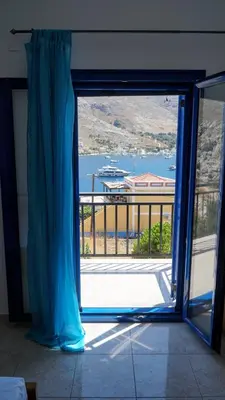 an open glass door with a view of a balcony at Irene Double Apartment Anoi in Symi